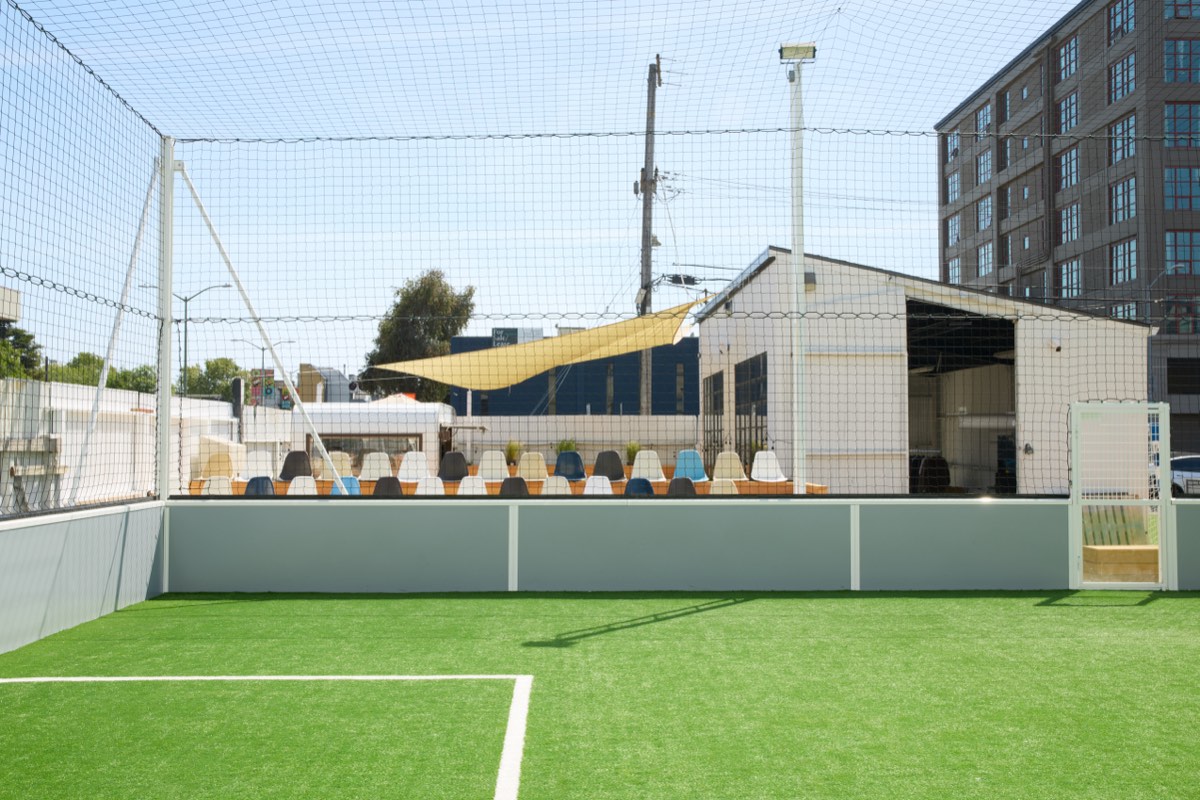 The outdoor 5v5 pitch at NSC, with sideline seating and the clubhouse behind